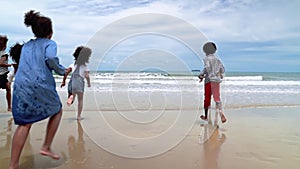 Slow motion, african-American children are holding hands running on the beach in the summer