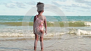 Slow motion,An African-American girl standing and looking at the waves on the beach