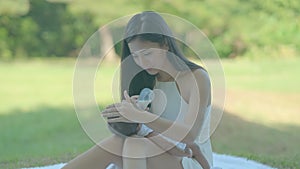 Slow motion of Asian beautiful mother give bottle milk to her newborn baby in park or garden with day light