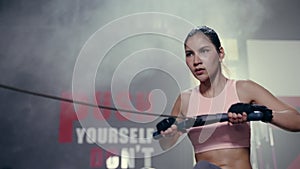 Slow motion, asian Female exercising in fitness club. Fitness young asian woman using rowing machine in the gym. Woman doing cardi
