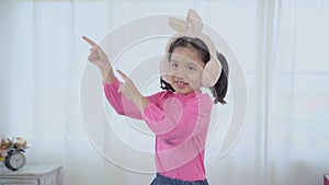 Slow-motion, Asian funny kid dancing, jumping on sofa at home,  adorable girl pretend to be a dancer, enjoy with music create own