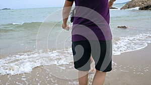 Slow-motion Asian little girl playing with mother on the beach with nature sea wave coast for summer vacation concept