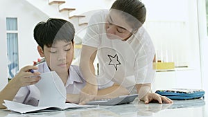 Slow motion of Asian mother helping her son doing homework on white table.