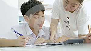 Slow motion of Asian mother helping her son doing homework on white table.