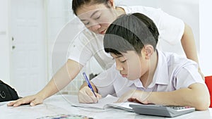 Slow motion of Asian mother helping her son doing homework on white table.