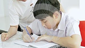 Slow motion of Asian mother helping her son doing homework on white table.