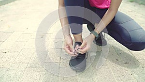Slow motion - Asian runner woman tying shoes. Healthy young female in sport clothing prepare to warm up her body before doing