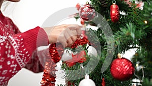 Slow motion of asian woman decorating christmas tree with tinsel garland. Xmas