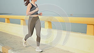 Slow motion athlete woman running at the beach road. Asian female runner endurance training in summer. Healthy lifestyle and sport