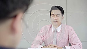 Slow motion - Attractive Asian man during job interview. Businessman in formal wear reading paper documents.