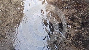 SLOW MOTION Autumn rain water drops falling into big puddle on asphalt, flooding the street