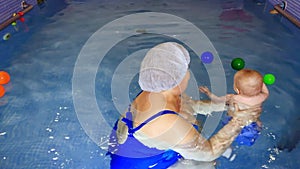 slow-motion. baby swimming. child in the pool with the coach.