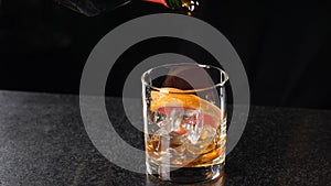 Slow motion of bartender pouring spirit out of bottle into glass. Close-up. Bar in night club with dark background. Full