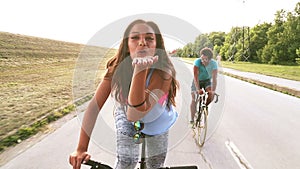 Slow motion of beautiful woman sending kisses while cycling with friends, graded