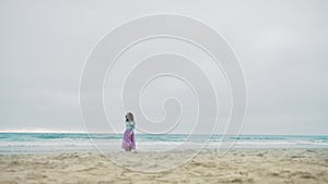 Slow motion beautiful young woman wearing tulle lilac pink skirt running beach
