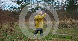 Slow motion. A boy in a yellow jacket stands and looks at the beauty of the forest and the planet earth. Watch and dream