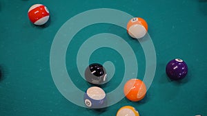 Slow motion: breaking racked pool balls on teal billiard table - close up