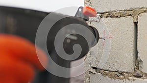 SLOW MOTION,: Builder working uses an electric drill to mount a wall panel. Man drills hole using perforator. Male hands