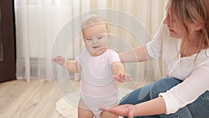 Slow motion of Caucasian cute baby girl boy child learn to walk with parent. smiling young mother support toddler infant