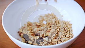 Slow motion of cereal flakes falling into a breakfast plate. The concept of breakfast, a healthy diet, granola with
