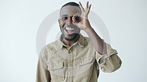 Slow motion of cheerful African American man looking at camera through OK hand gesture smiling