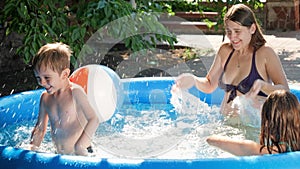 Slow motion of cheerful happy family splashing water and having fun at outdoor swimming pool at house backyard garden