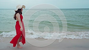 Slow-motion of cheerful woman in red dress walking on sea beach