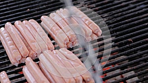 Slow motion: chef grilling fresh meat sausages on big round hanging grill