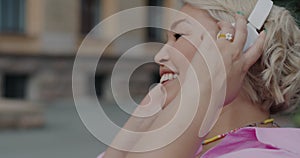 Slow motion close-up of attractive Asian lady putting on headphones dancing enjoying music in city