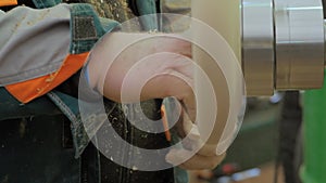 Slow motion, close up: carpenter using sandpaper, sanding piece of wood on lathe