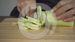 Slow motion - Close up of chief woman making salad healthy food and chopping cucumber on cutting board in the kitchen