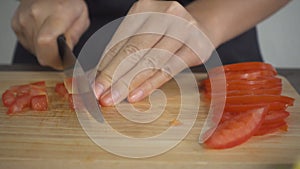 Slow motion - Close up of chief woman making salad healthy food and chopping tomato on cutting board in the kitchen