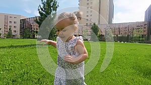 Slow motion close up: cute baby girl walking in the city park and exploring world aroun her, summer sunny day.