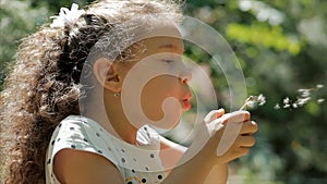 Slow Motion Close-Up Shot of Cute Little Girl Carefree Blowing a Dandelion Outdoors on a Sunset. Concept of Happy