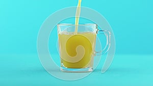 Slow motion close-up shot of fruit orange multifruit juice cold beverage drink pooring into glass mug with handle blue