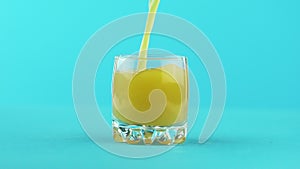 Slow motion close-up shot of fruit orange multifruit juice cold beverage drink pooring into small beautiful glass blue