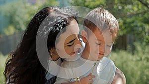 Slow Motion Close-Up Shot of Happy Mother Hugging Her Child and Gently a Carefree Blowing a Dandelion Outdoors. Concept