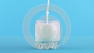Slow motion close-up shot of milk cold beverage drink pooring into small beautiful glass blue background in studio
