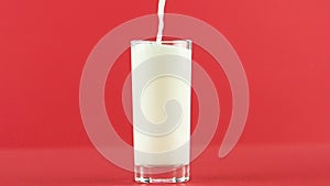 Slow motion close-up shot of yellow lemon fizzy lemonade soda cold beverage drink pooring into glass red background in