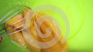 Slow motion close-up of someone preparing a homemade omelet or for baking mix eggs with a metal whisk in a plastic bowl. The proce