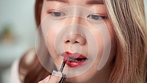 Slow-motion close-up video, pretty Asian women are using paintbrush, apply lipstick to the mouth