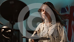 Slow motion. Close-up. A young talented girl musician is diligently playing a composition on an electronic drum kit