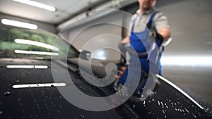 Slow motion closeup blowing off water from freshly washed black car with air. Car wash and detailing service.