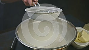 Slow motion closeup woman hands hold empty sieve above bowl with sifted flour