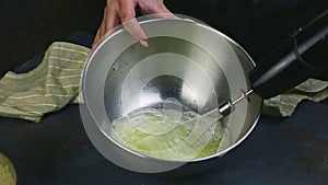 Slow motion closeup woman hands whisking egg whites by whisk in deep metal bowl