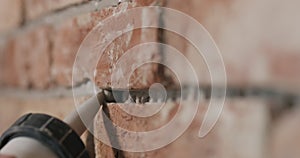 Slow motion closeup of worker filling seam between bricks with mortar from sealant gun