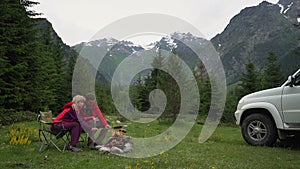 Slow-motion. couple roasting sausages over bonfire in camping in mountains