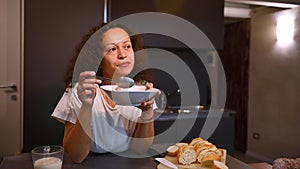Slow motion. Curly brunette woman taking her breakfast in the morning, eating cereals with milk
