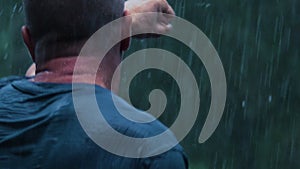 Slow motion: A drenched man shadowboxes in the pouring rain in a thunderstorm