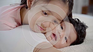 Slow motion of Elder sister kissing newborn baby while lying on bed, adorable girl kiss cheeks toddler with love and care. cute li